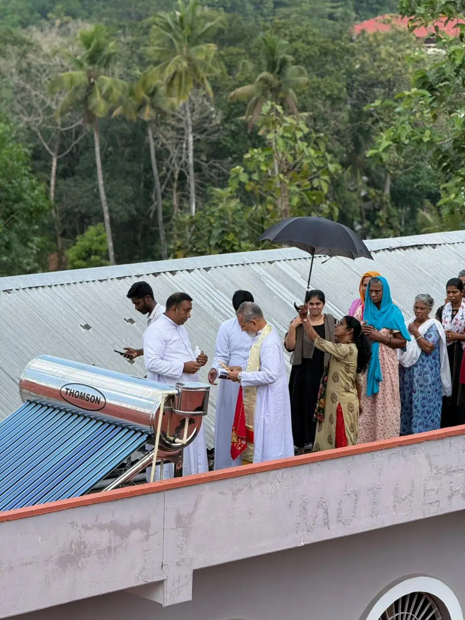 A priest blesses newly installed facilities at Mother Teresa Home while residents and staff look on.